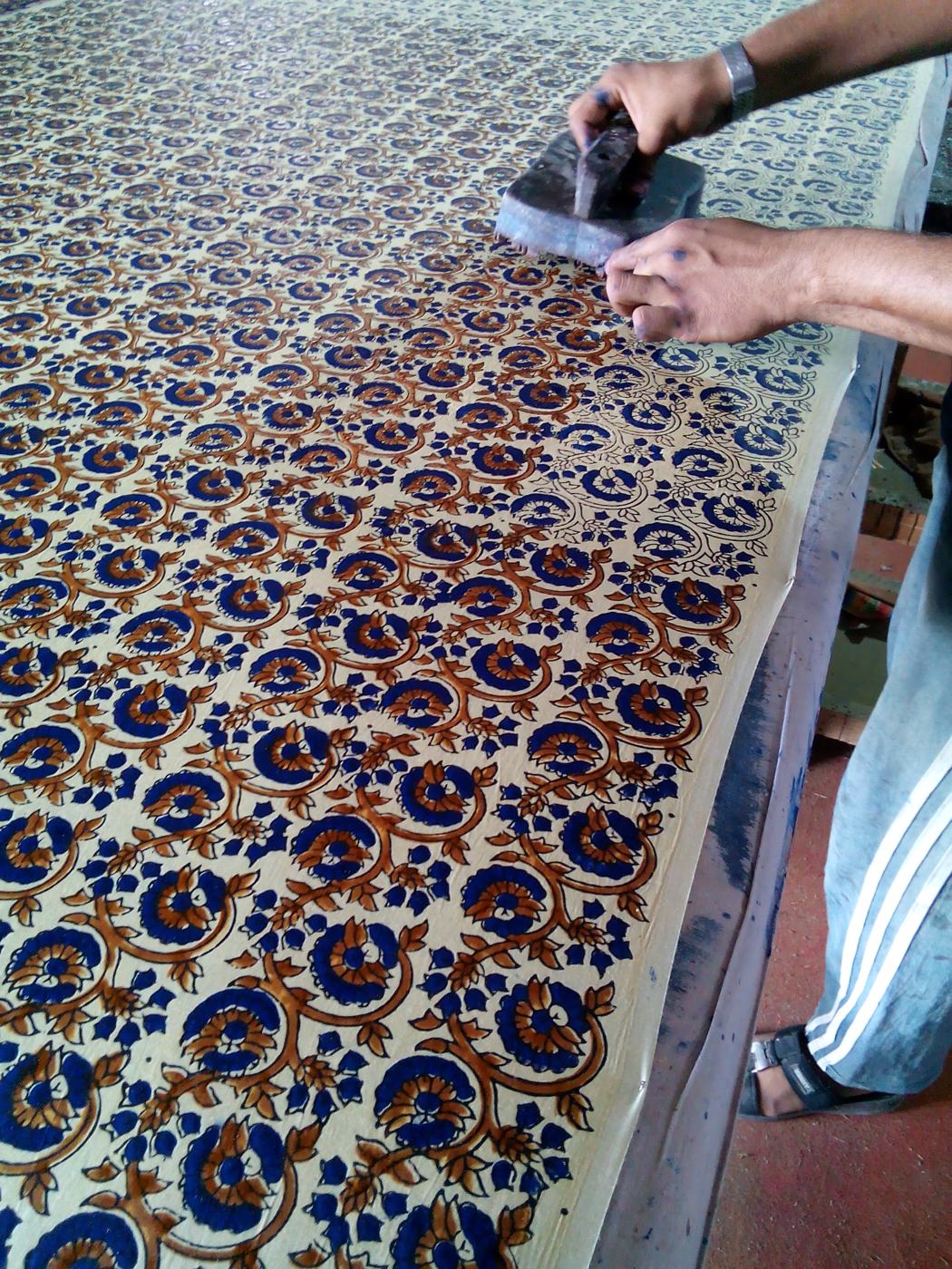 Hand block printed fabric in indigo and madder being worked on at the printing table
