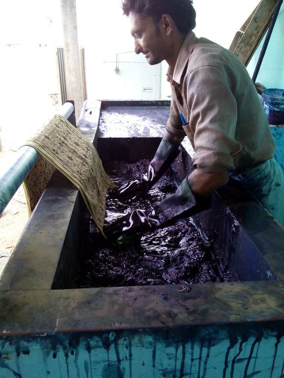 Artisan washing printed fabric in a dye tank