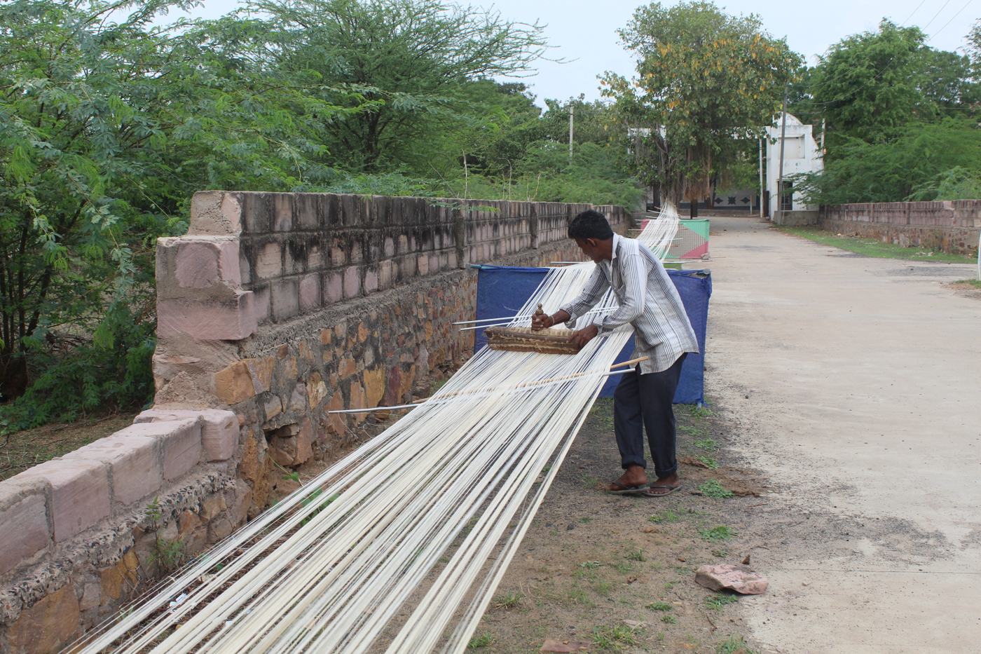 Weaver stretching a long warp of Kala cotton yarn