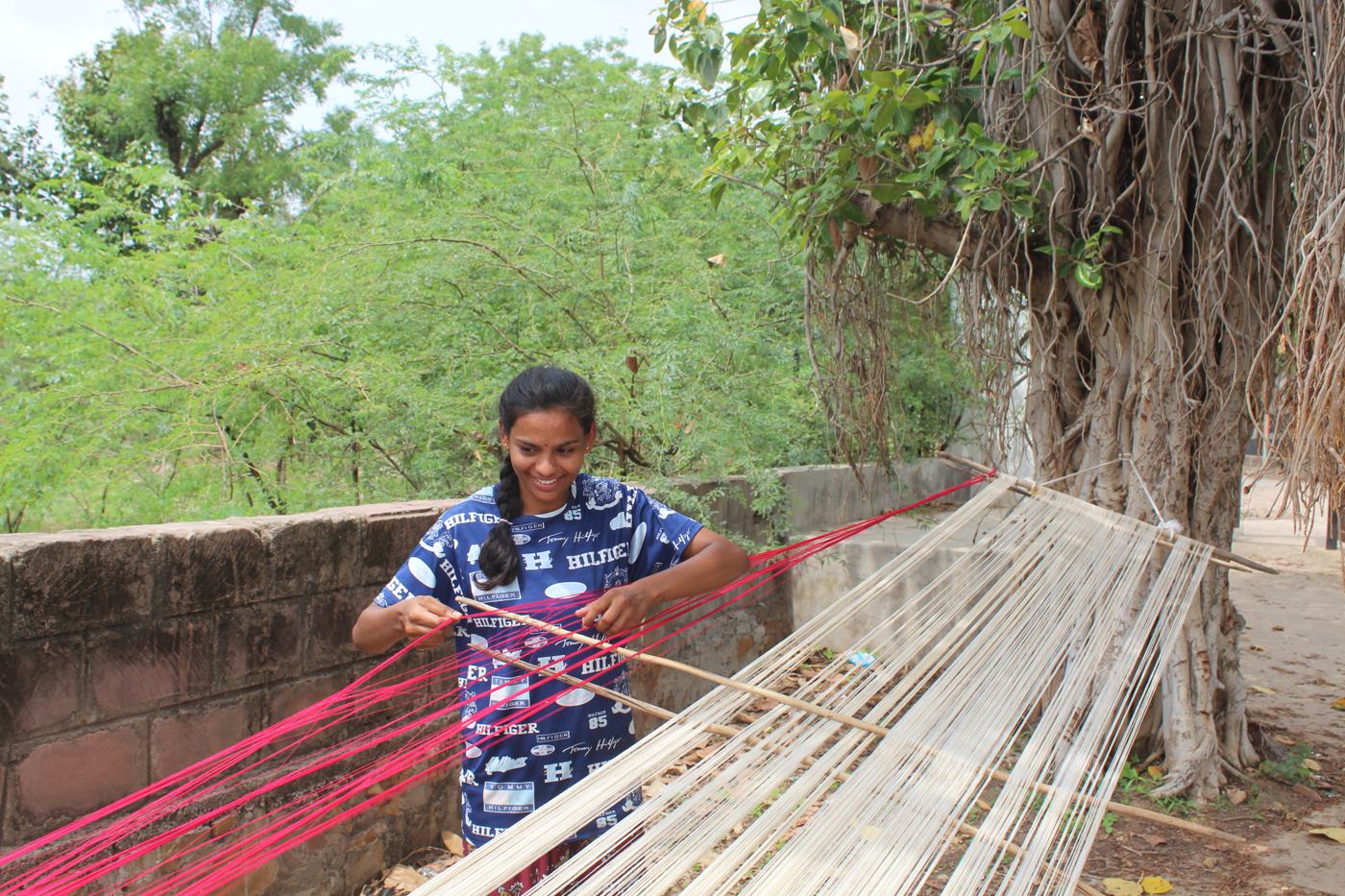 A young woman working with pink and white warp threads